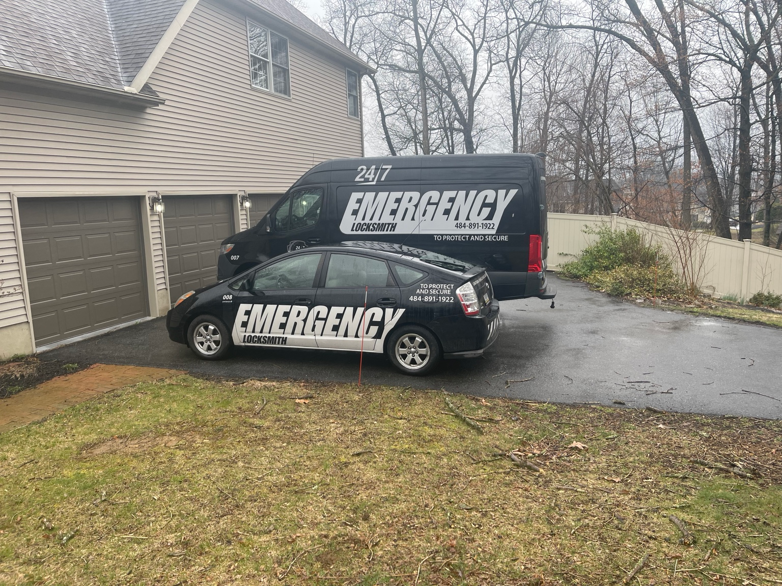 Branded Emergency Locksmith van and service car parked in a driveway